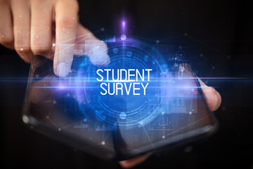 Young man holding a foldable smartphone with STUDENT SURVEY inscription, educational concept