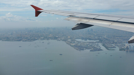 The plane flies against the background of the city of Jakarta. Indonesia.