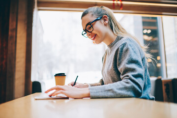 Successful female student searching information on mobile phone while preparing for exam 