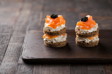 Smoked salmon with creamy cottage cheese and black caviar. Catering finger food, snack, mini canapes.