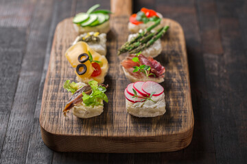Set of different mini canapes served on a wooden board. Catering finger food.