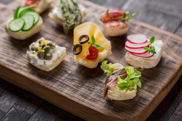 Set of different mini canapes served on a wooden board. Catering finger food.