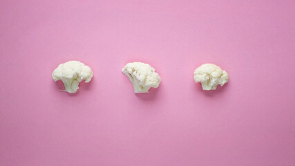 Three slices of cauliflower on a pink background. Three slices of cabbage on a bright substrate. Creative food for design.