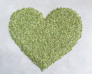 Heap of green chopped pea in the shape of heart isolated on light gray background. Heart shaped green dry chopped peas.