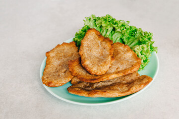 Homemade small load of bread with whole grain grains. Baked bread in a pan in a light turquoise plate on a gray-white background. Green lettuce leaves. Healthy eating concept.
