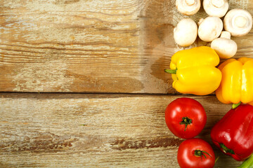 Yellow and red peppers, tomatoes, mushrooms on the edge of the table from rough boards