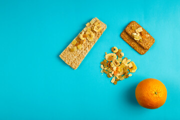 diet bread, orange and granola on a blue background.
