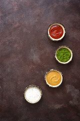 Collection of various sauces in the bowl: tomato, pesto, creamy with greens and mustard on a dark rustic background. Top view, copy space.