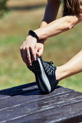 Close up of vertical shot of girl stretching. Taking her foot with both hands on a bench