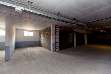 Parking spaces in the basement of an apartment building are separated by walls. some Parking spaces have roller shutters