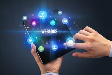 Businessman holding a foldable smartphone with WEBLOGS inscription, social media concept