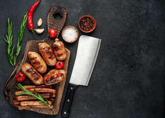 Different grilled sausages with spices and
rosemary, served on a cutting board on a stone background with copy space for your text