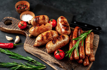 Different grilled sausages with spices and
rosemary, served on a cutting board on a stone background