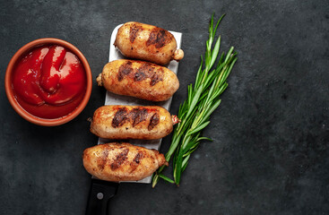 Grilled sausages over a meat knife on a stone background with copy space for your text