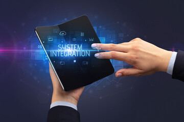 Businessman holding a foldable smartphone with SYSTEM INTEGRATION inscription, cyber security concept