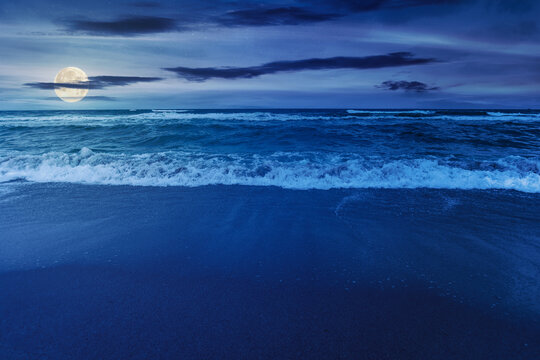 beach and sea on a cloudy night. beautiful view of waves rolling the coast beneath a glowing sky in full moon light