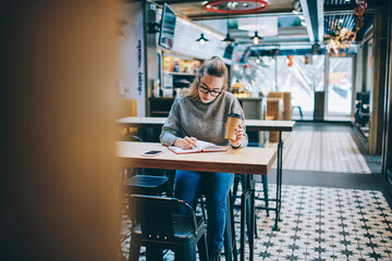 Selective focus on female hand making notes of information in textbook