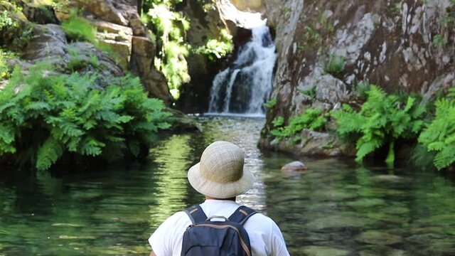 Image of a tourist looking and contemplating the waterfall next to nature in a region of Portugal
