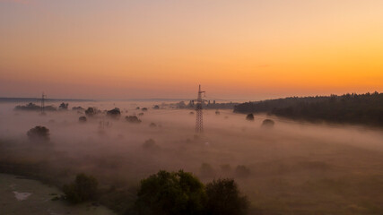 High voltage electricity transfer lines and pylon in a fog