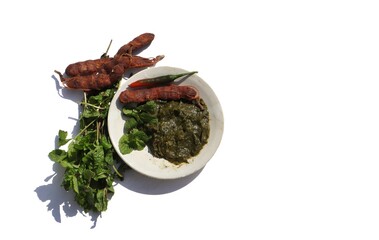 Pudina Chutney or Field Mint Leaves Paste in a Plate with Tamarinds  and Leaves on White Background with Copy Space for Texts Writing
