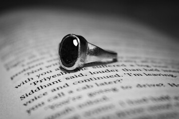 black and white photo of a book and a ring