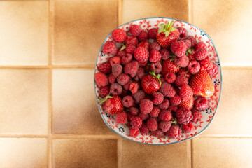 Vue du dessus d'une assiette de fraises et de framboises fraîches dans une cuisine