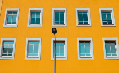 View from the bottom of the lantern and a yellow wall with Windows in white frames. Street photo. Selective focus