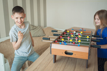 Children play table football, have fun and laugh. The boy won and rejoices