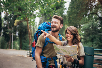 Couple hiking trough forest. Using map to get good direction.