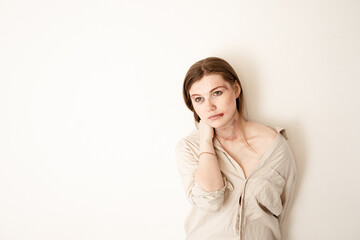 a girl in a shirt touches her bruises, stands on a white background, the victim of domestic violence, left the place for advertising