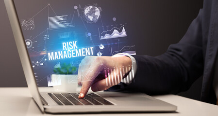 Businessman working on laptop with RISK MANAGEMENT inscription, new business concept