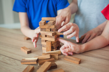 Fototapeta na wymiar Children playing on wooden blocks, game, learning and development concept. Boy and two girls Close-up on cubes