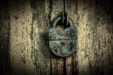 The old rusty metal door is closed with a large metal padlock. Concept: closed, no passage. The...