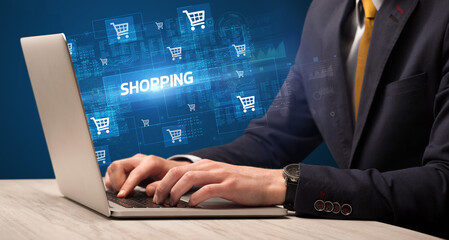 Businessman working on laptop with SHOPPING inscription, online shopping concept