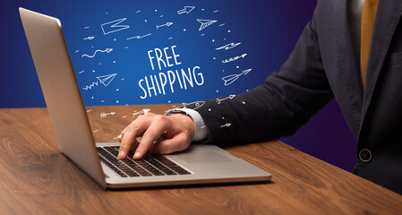 Businessman working on laptop with FREE SHIPPING inscription, online shopping concept