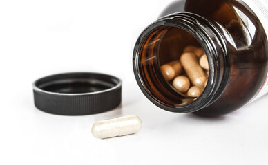 One pill out of plastic bottle and bunch inside. Spilled capsule ,container and black cap