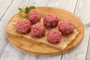 Raw meatball over wooden background