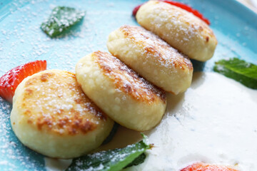 Cheesecakes in a creamy sauce with strawberries and mint.