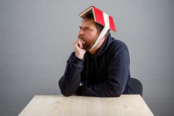 a bearded man with a book on his head hopes that knowledge is transmitted through carrying a book