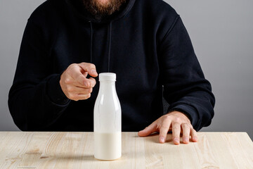 a bottle with milk on the table, a hand indicates to drink it or not to drink it