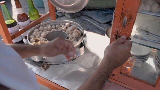 bakso. indonesian famous meatball street food vendor close up hand serving