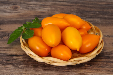 Yellow tomato heap in the wooden bowl