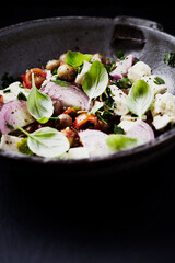 Salad with Olives, Cherry Tomatoes, Feta Cheese and fresh Basil on black Stone Background. Healthy Snack Idea. Close up. Copy space.