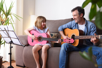 Father daughter playing guitar looking at each other with complicity