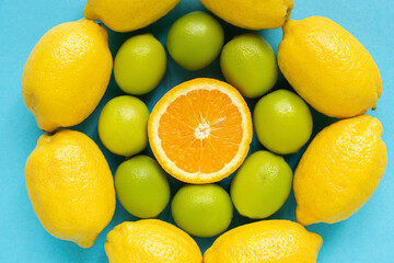 top view of ripe yellow lemons, orange and limes arranged in circles on blue background