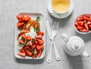 Tasty breakfast - cottage cheese fritters with strawberry and green tea on a light background, top...