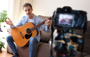 Fototapeta na wymiar Video Blogger doing review of a guitar recording at home