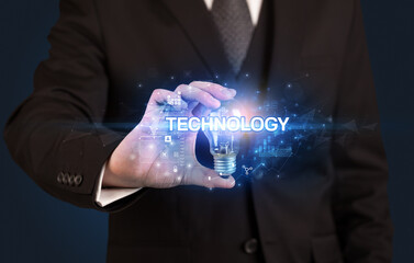 Businessman holding light bulb with TECHNOLOGY inscription, innovative technology concept