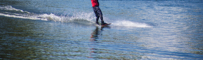 The man does wakeboarding on the water in the summer in a helmet and wetsuit.