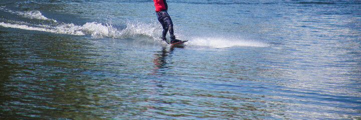 The man does wakeboarding on the water in the summer in a helmet and wetsuit.